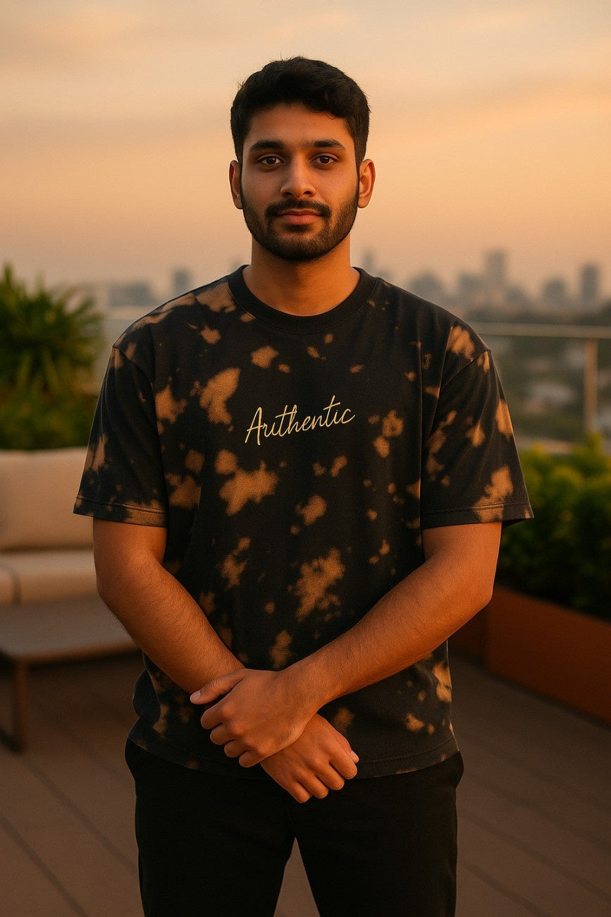 Man wearinga black tie-dye Embroidered 'Authentic' Unisex Oversized t-shirt  from The Edi Archive, standing on a rooftop with cityscape in the background.