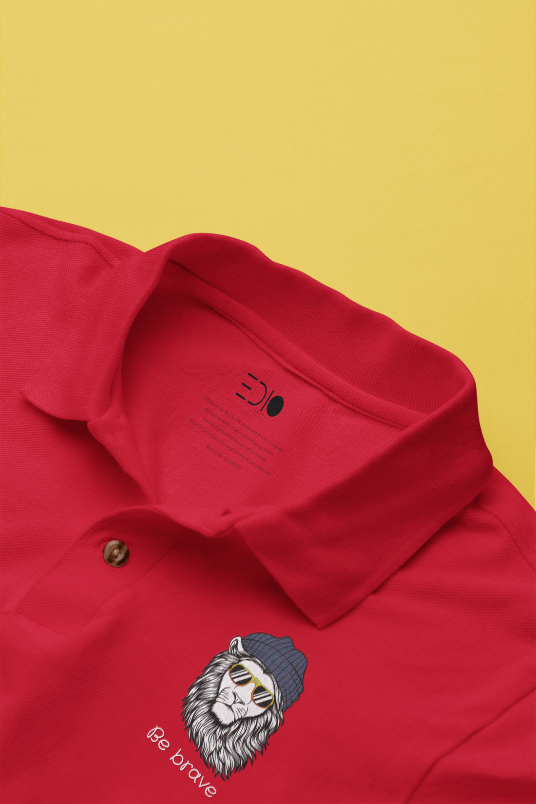 Close-up of The Edi Archive’s ‘Be Brave’ red polo T-shirt showing the lycra ribbed neck and lion cap graphic on the chest.