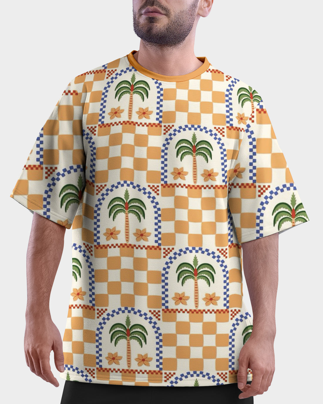 Man wearing a colorful patterned Desert Palm Unisex Oversized T-Shirt from The Edi Archive, and shorts on a beach
