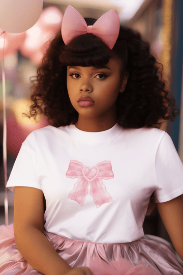 Girl wearing white Lacey Affair women’s t-shirt from The Edi Archive, with watercolor pink bow and pearl heart at the center, styled in soft romantic coquette aesthetic.