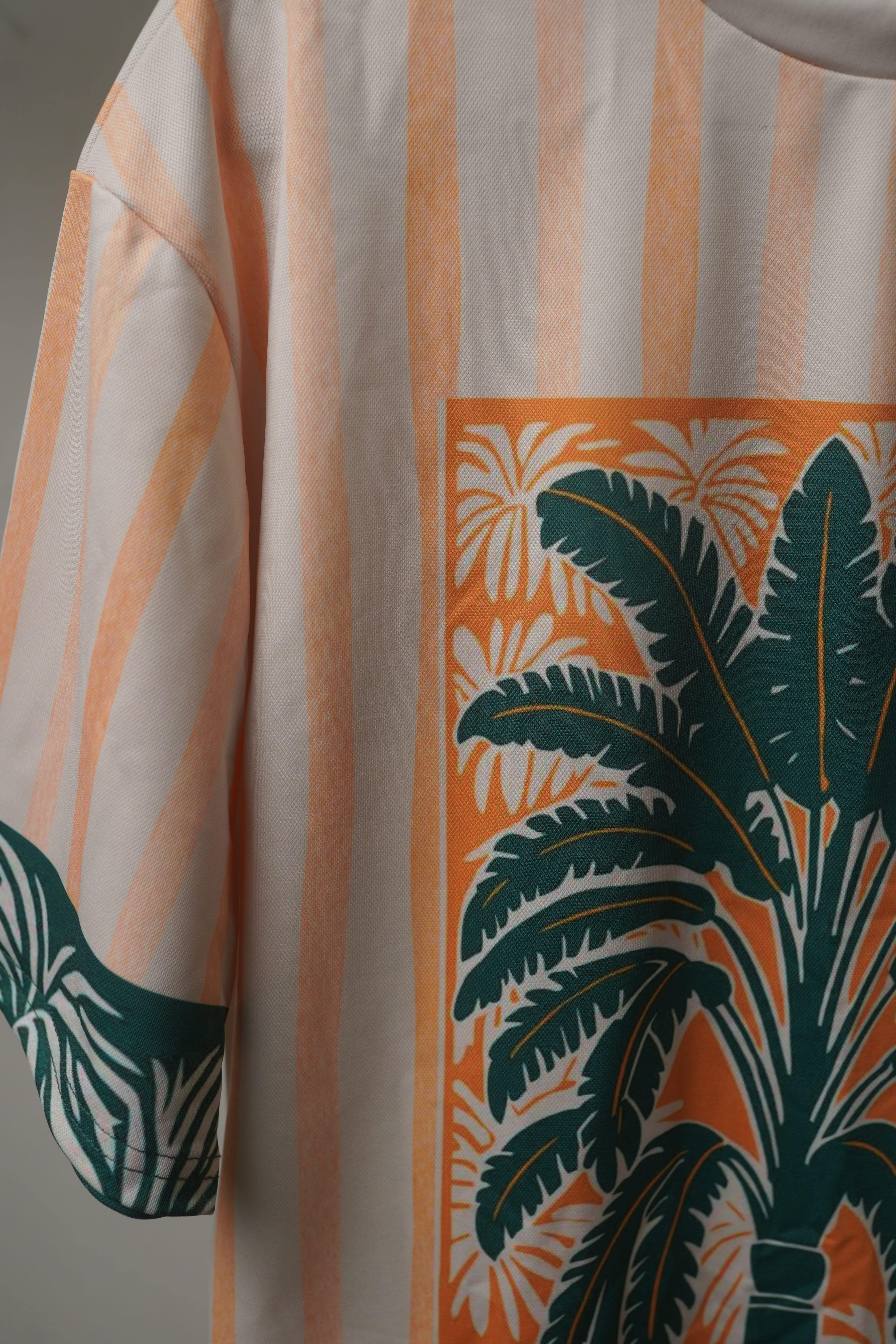 Close-up of Azure Palms Unisex Oversized t-shirt from The Edi Archive,  sleeve with detailed palm leaf print