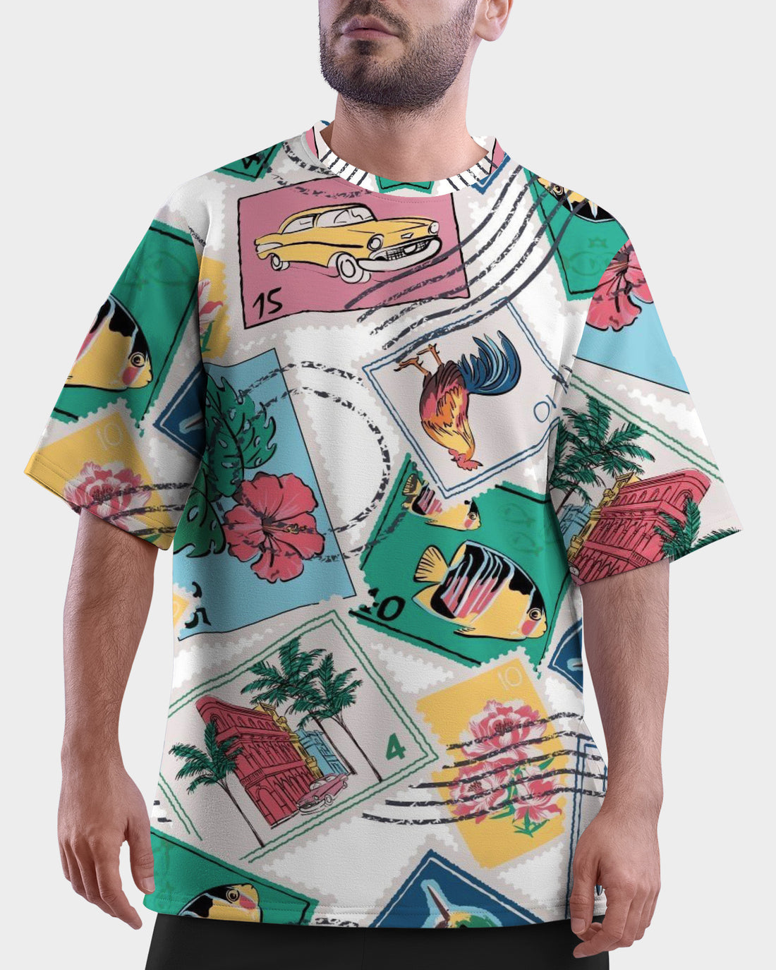 Man wearing a colorful graphic Travelesque Unisex Oversized T-Shirt from The Edi Archive, with a tropical design, standing outdoors with palm trees and blue sky in the background.