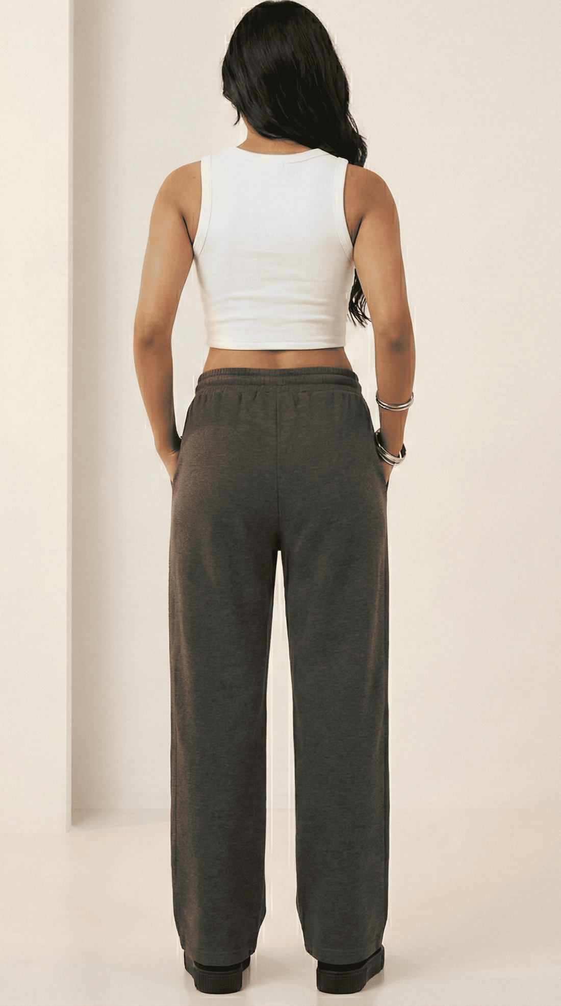 Woman wearing a white tank top and charcoal comfy chaos unisex sweatpants from The Edi Archive, front view.