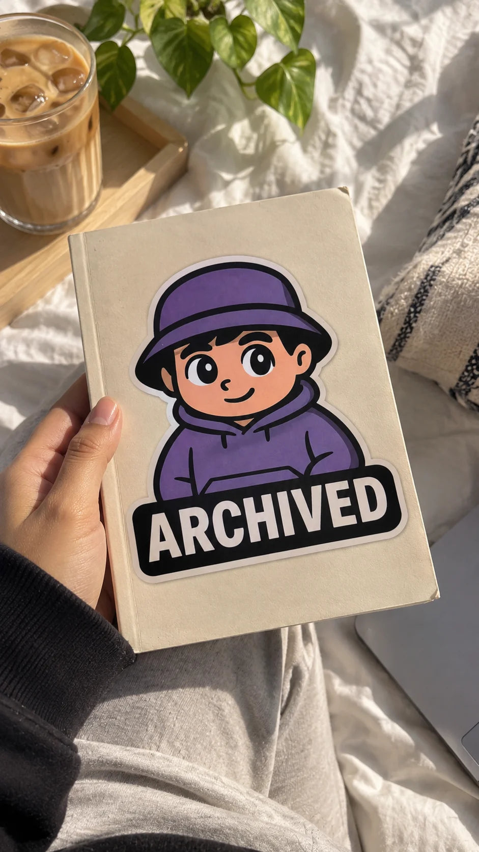 Archived A5 Notebook by The Edi Archive from The Side Quest Collection, beige notebook with purple character and Archived artwork held in hand