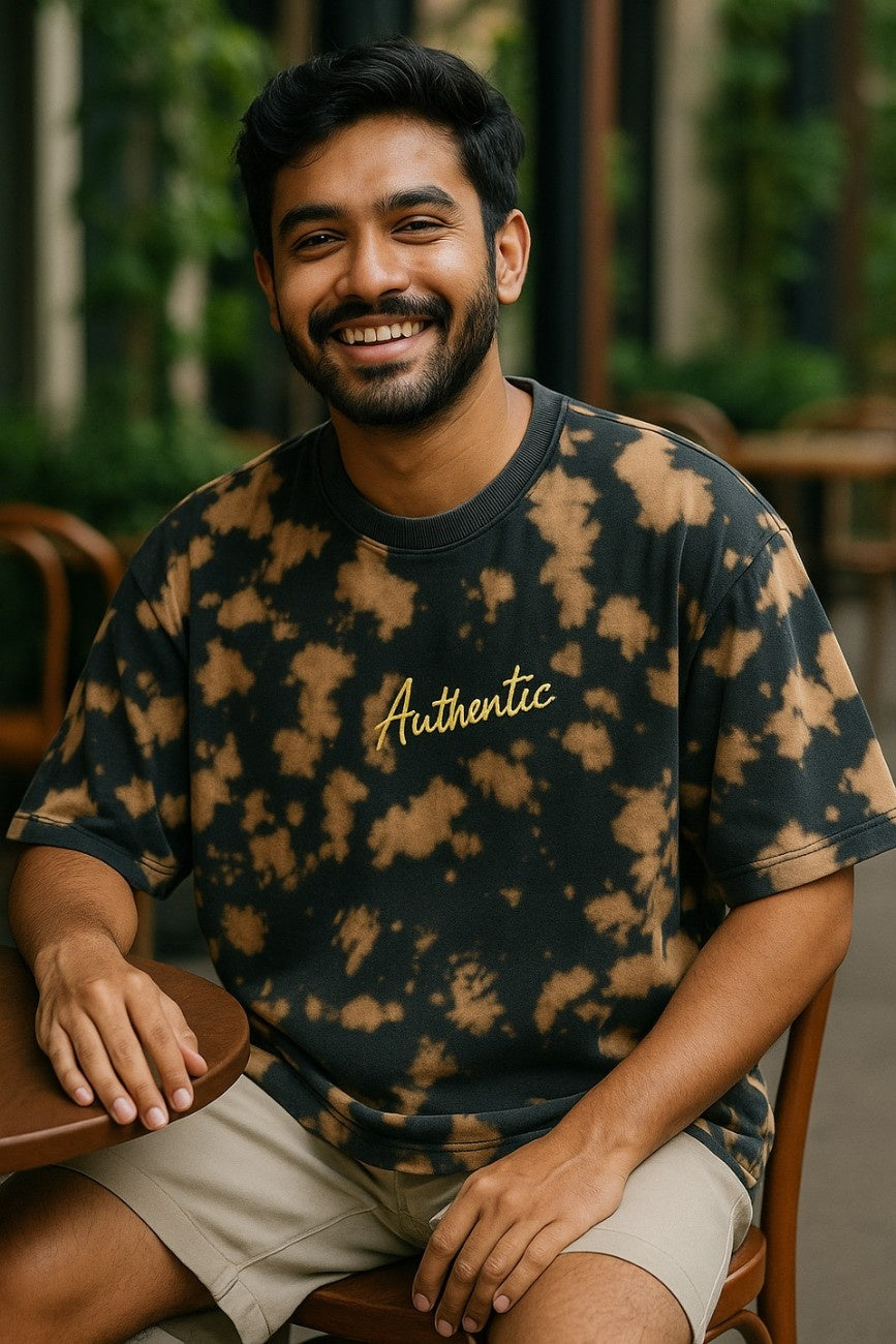 Man wearing a black tie-dye Embroidered 'Authentic' Unisex Oversized t-shirt  from The Edi Archive, and blue jeans walking on a colorful street.