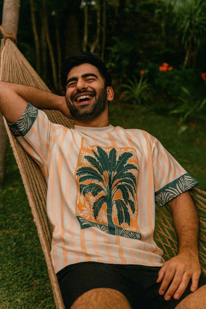 Man relaxing in a hammock wearing Azure Palms Unisex Oversized t-shirt from The Edi Archive, with a palm tree design.