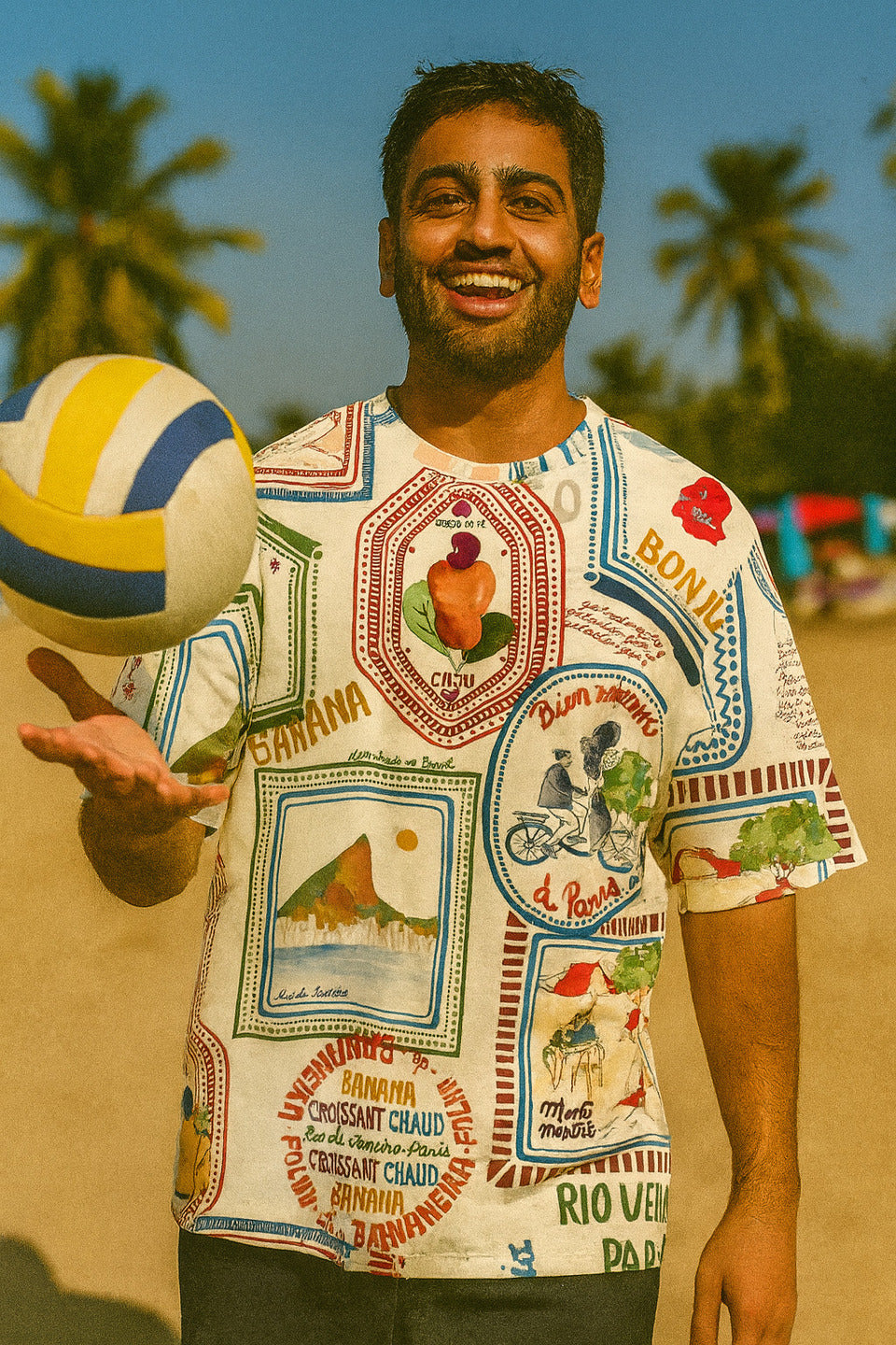 Man holding a volleyball on a beach with palm trees in the background wearing Bonjour Unisex Oversized T-Shirt From The Edi Archive,