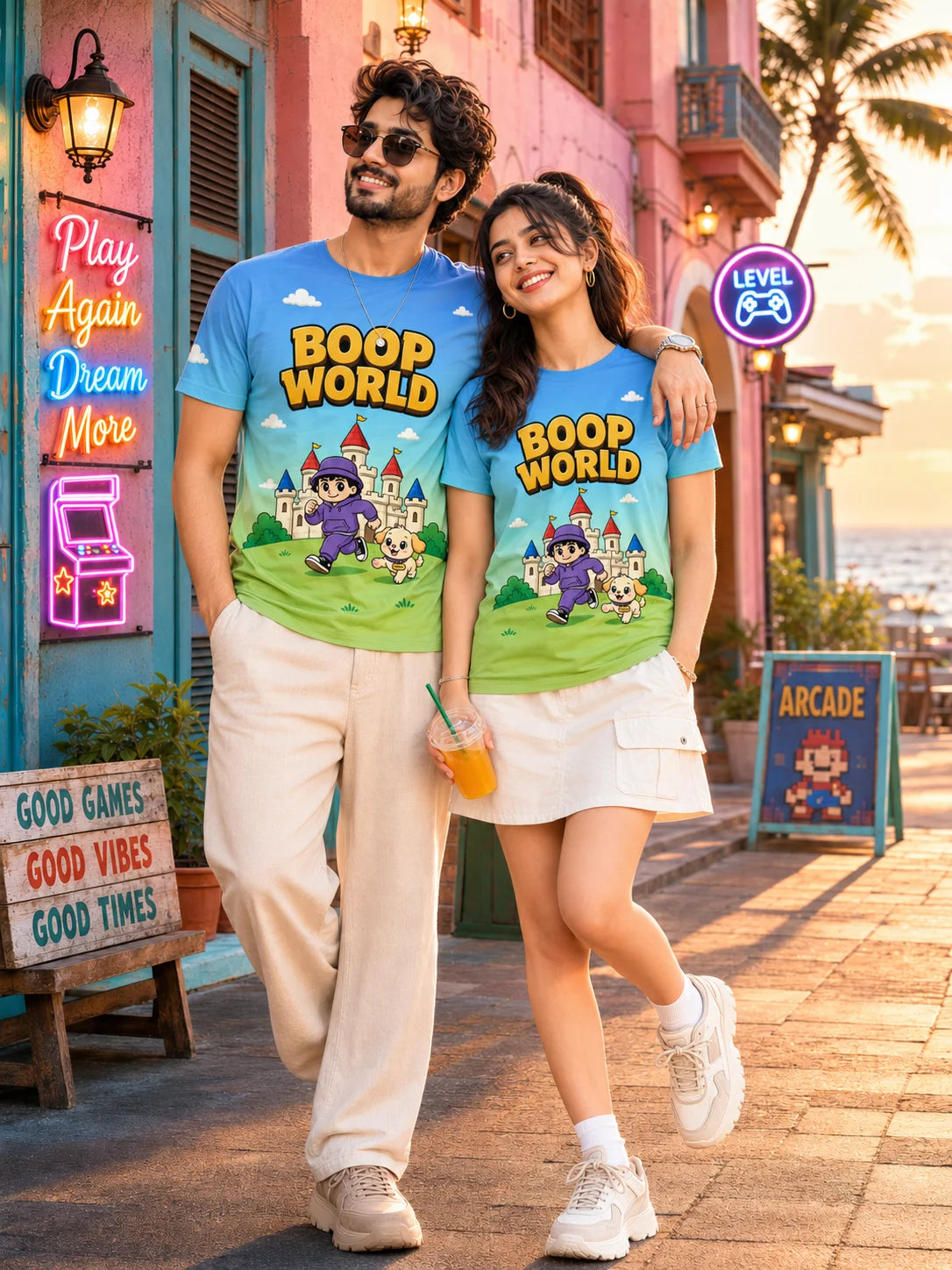 Couple posing in matching Boop World all over print unisex t-shirts with neon arcade signs behind them, Boop World Unisex T-Shirt, Boop Squad Collection, The Edi Archive