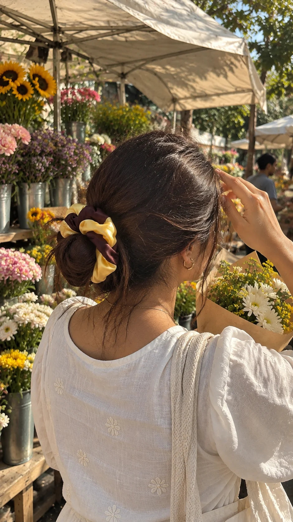 Butter Lines Scrunchie by The Edi Archive from The Side Quest collection, featuring a brown and butter-yellow striped design worn in a woman's hair at a flower market