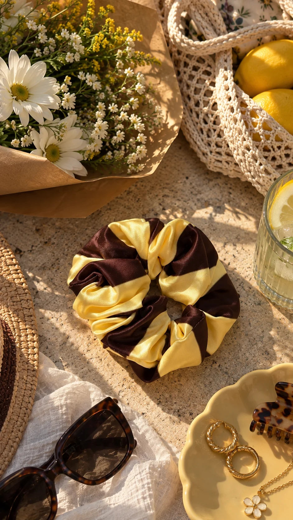 Butter Lines Scrunchie by The Edi Archive from The Side Quest collection, featuring a brown and butter-yellow striped design styled with flowers, sunglasses and jewellery