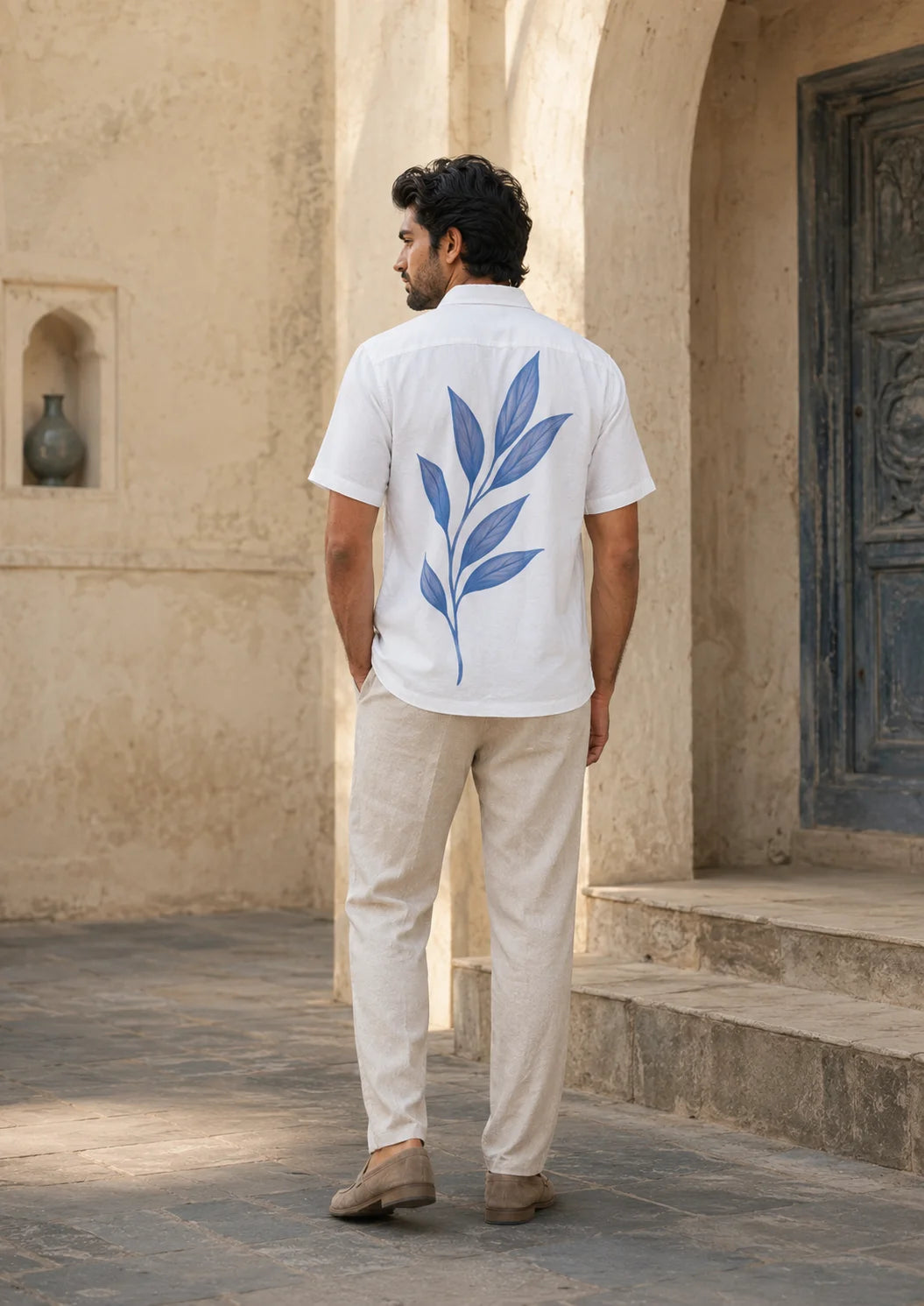 Back view of a man in a white short sleeve shirt showing the large blue botanical leaf print across the back, Ink Leaf Hawaiian Shirt, Tropical Drop, The Edi Archive