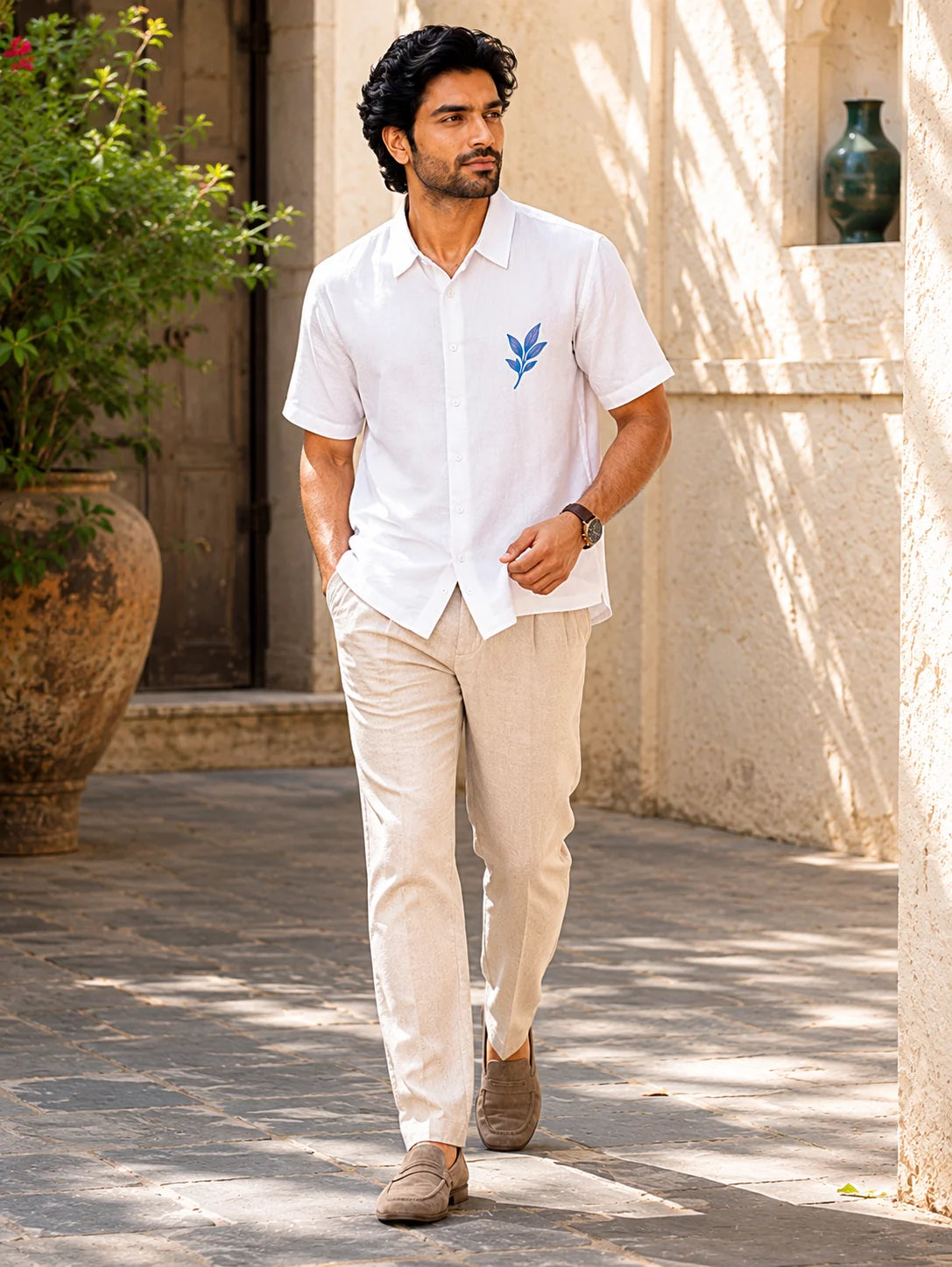 Man walking through a sunlit courtyard in a relaxed fit white cotton shirt with a blue leaf chest print, Ink Leaf Hawaiian Shirt, Tropical Drop, The Edi Archive