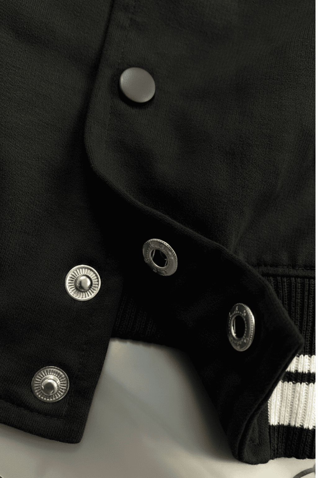 Close-up of a black varsity jacket with silver buttons from the Custom Archive Collection by The Edi Archive