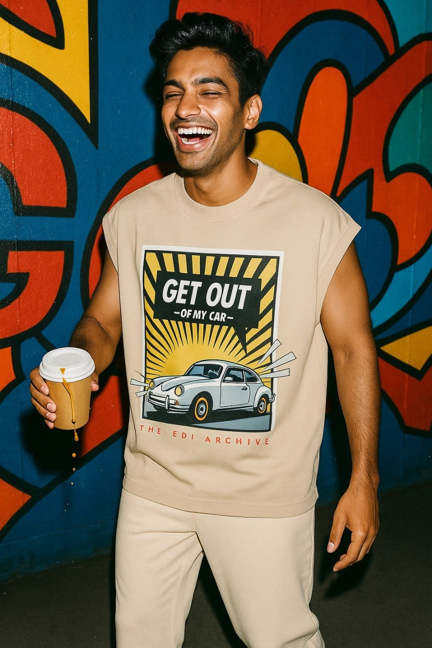 Get Out Of My Car Unisex Oversized Graphic Tank Top Off White styled with matching track pants model laughing holding coffee against graffiti wall The Edi Archive