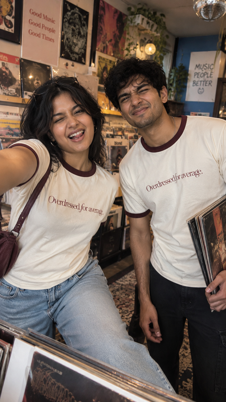 Overdressed Ringer T-Shirt by The Edi Archive featuring a cream 100% cotton ringer tee with burgundy ribbed trim and “Overdressed for average.” graphic, styled on two people at a vinyl record store