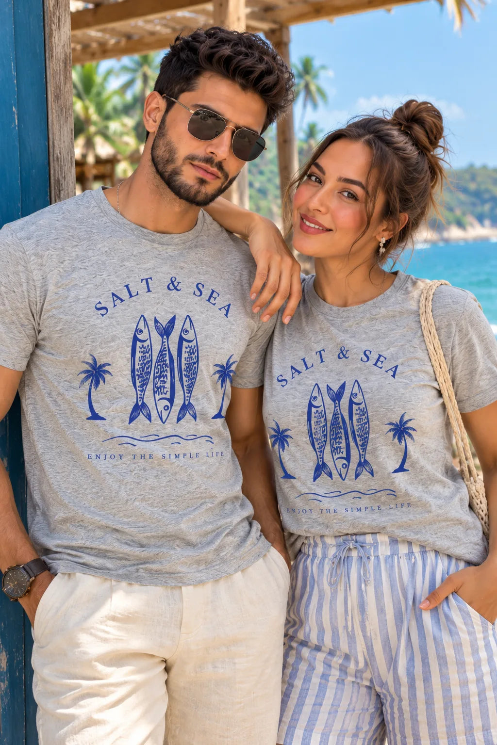 Salt & Sea Unisex T-Shirt by The Edi Archive, Tropical Drops Collection, in grey melange with a blue fish and palm tree graphic, styled on a South Asian couple.