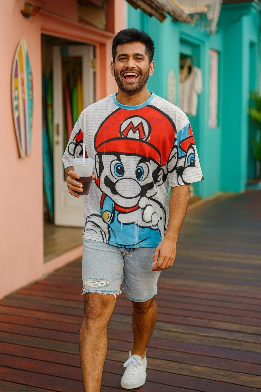 Man wearing Super Mario Unisex Oversized T-Shirt From The Edi Archive, with a character design, standing on a wooden floor.