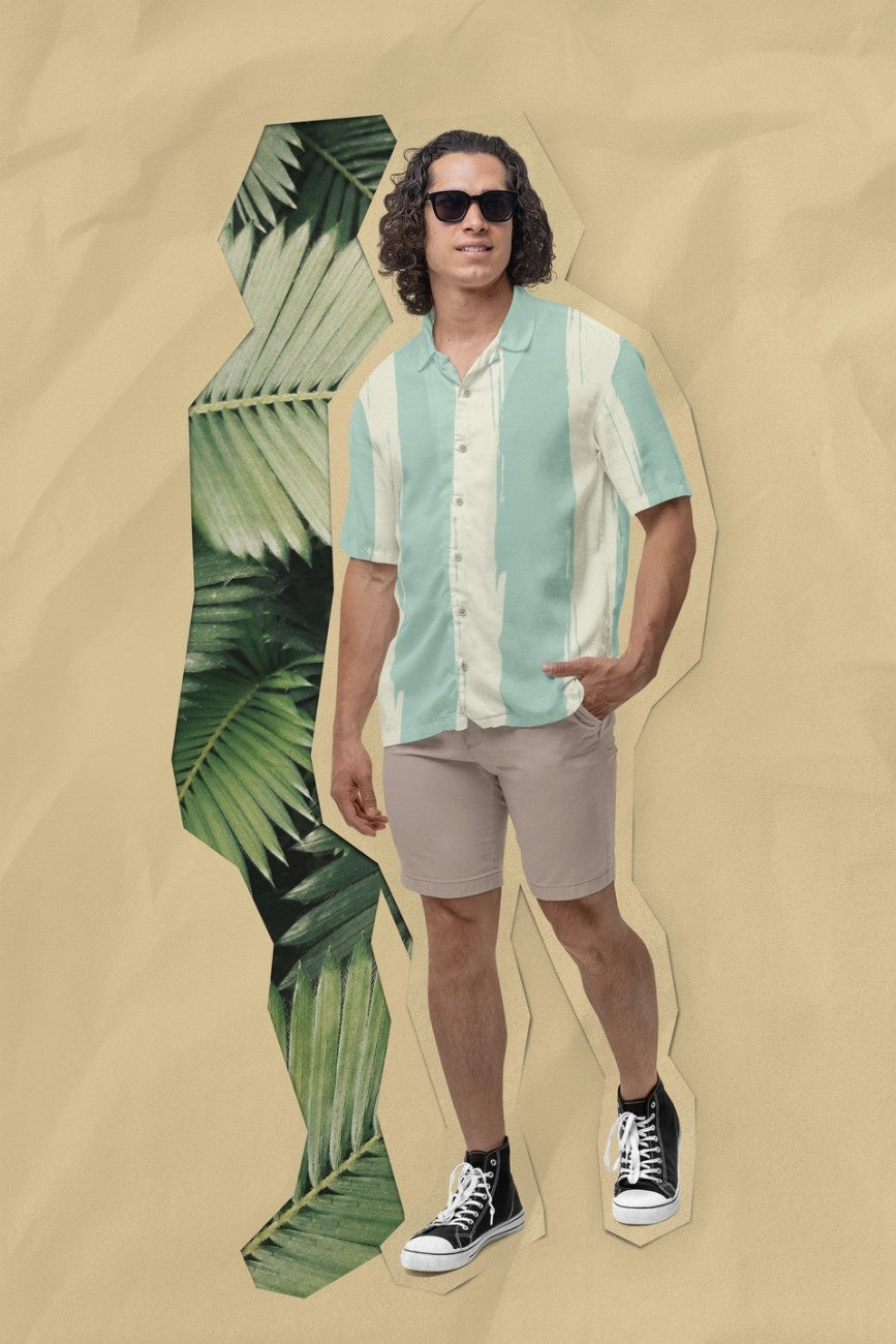 Man wearing a Teal Away Men's Hawaiian Shirt from the Tropical Drops from The Edi Archive, and beige shorts with a palm leaf on a beige background