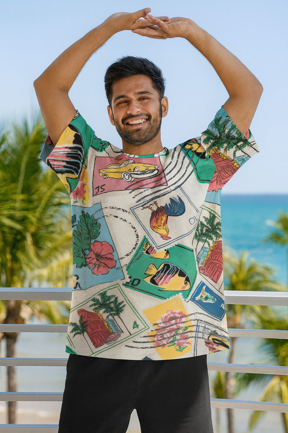 Man wearing a colorful graphic Travelesque Unisex Oversized T-Shirt from The Edi Archive, with a tropical design, standing outdoors with palm trees and blue sky in the background.