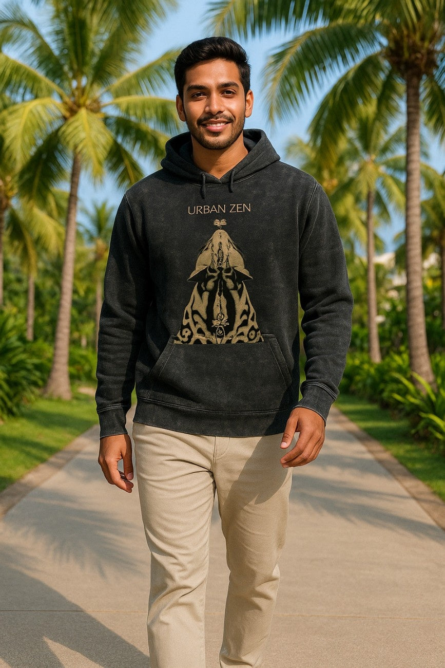Man wearing a stone-washed black hoodie with 'Urban Zen' design from The Edi Archive, in a tropical setting