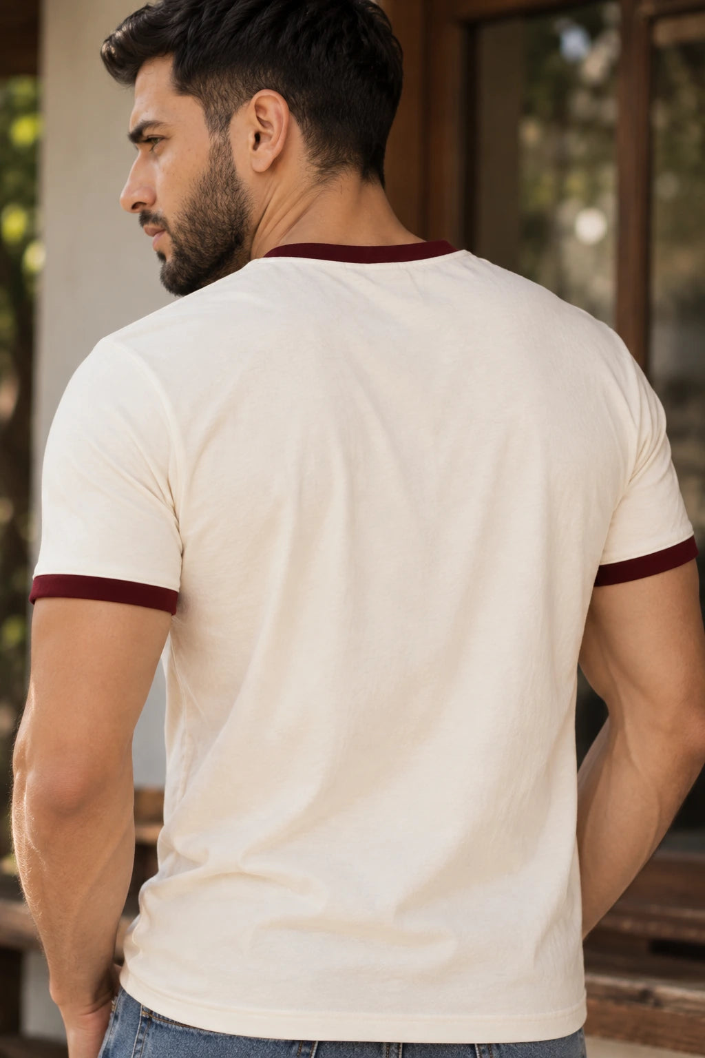 Back view of a man wearing the off-white regular-fit ringer T-shirt with maroon contrast neckline and sleeves from The Edi Archive, plain unprinted back.